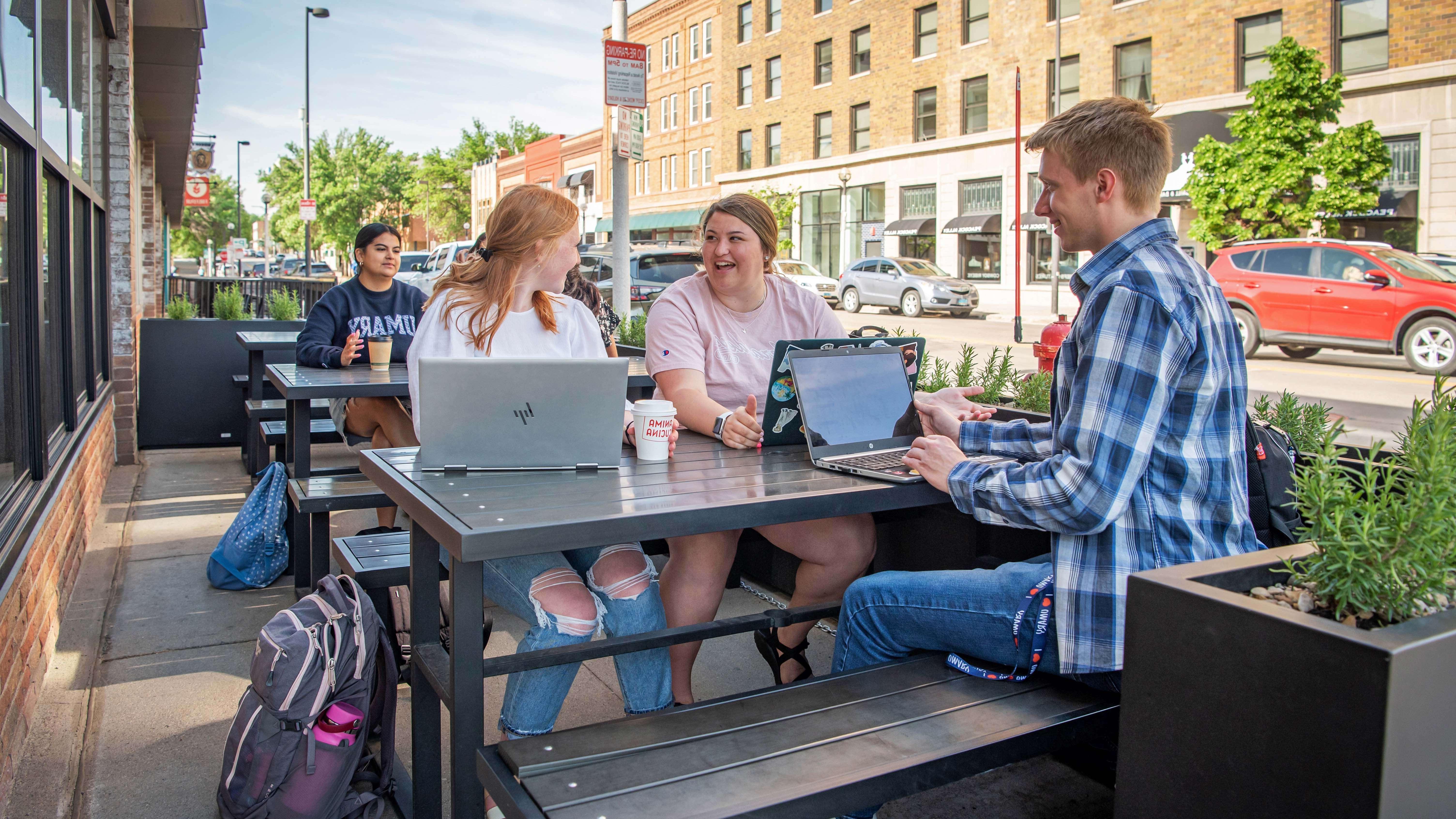 三个mg不朽情缘的学生坐在俾斯麦市中心一家餐厅外的野餐桌旁